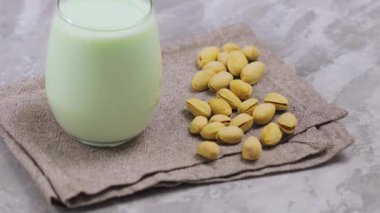 Gri arka planda fıstıklı şam fıstığı sütü. Vejetaryen bitkisi sütü. Eğil.