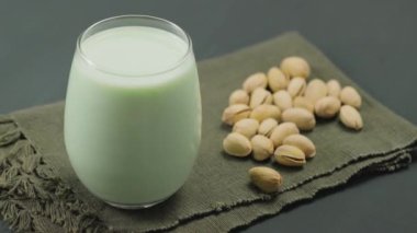 Cam kaplı organik şam fıstıklı süt ve koyu yeşil arka planda şam fıstığı. Sütsüz alternatif süt. Yukarı kaldır.