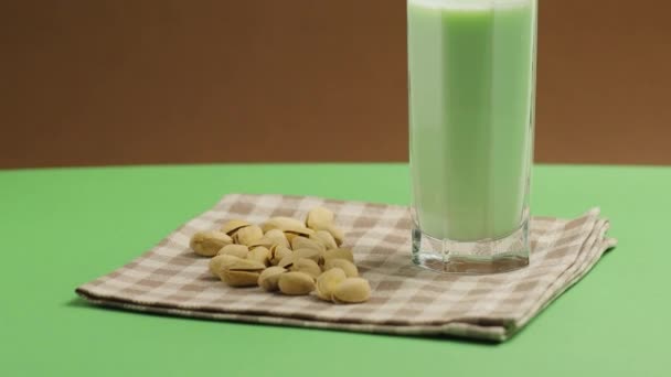 植物基天然开心果奶 倾斜向上铅球 亚麻布餐巾上有开心果牛奶的高杯 — 图库视频影像