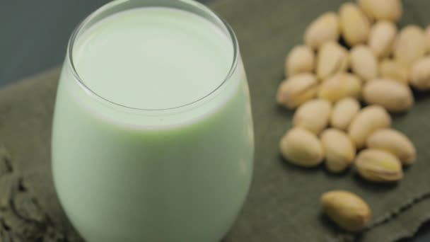 濃い緑色の背景にガラスとピスタチオの有機ピスタチオミルク 乳製品以外の牛乳 撃たれた — ストック動画