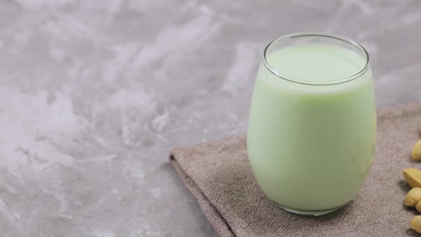 玻璃杯中的有机开心果牛奶 带有灰色背景的开心果 用植物制成的牛奶 潘宁相机拍摄 — 图库视频影像