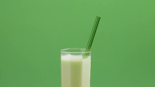 緑色のベージュの背景にピスタチオミルクのショットを下に傾ける ナプキンにピスタチオミルクとピスタチオと背の高いガラス — ストック動画