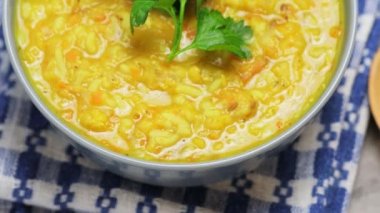 Kırmızı mercimek çorbası ve gri arka planda malzemeler. Bir kase mercimek çorbası ve keten peçetenin üzerinde tahta bir kaşık. Kamera hareketini yukarı kaldır