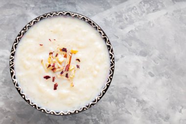 Gri arka planda sütlaçlı kase. Çimentoda kaju fıstığı ve badem ile pirinç kheer. Uzayı kopyala Üst görünüm