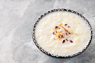 Gri arka planda sütlaçlı kase. Çimentoda kaju fıstığı ve badem ile pirinç kheer. Uzayı kopyala Üst görünüm