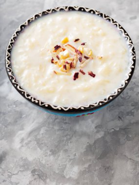 Gri arka planda sütlaçlı kase. Çimentoda kaju fıstığı ve badem ile pirinç kheer. Uzayı kopyala Üst görünüm