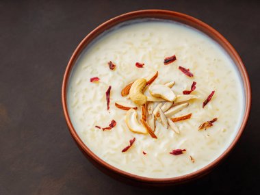 Kheer 'in fındık ve amberle süslenmiş kremalı pirinci. Siyah arka planda sütlaçlı kase. Üst görünüm