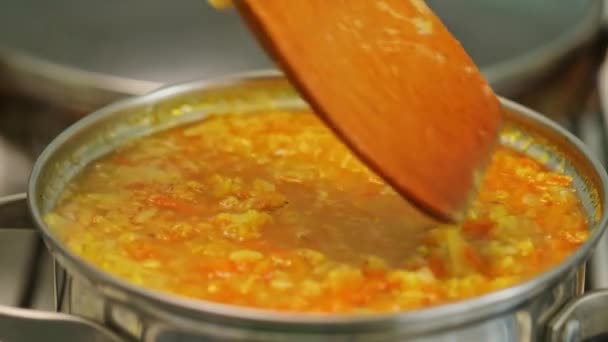 赤いレンズ豆のスープは木製のへらで攪拌されます 野菜とレンズ豆のスープを作るプロセス ラマダーンの伝統的なスープ 閉じろ — ストック動画