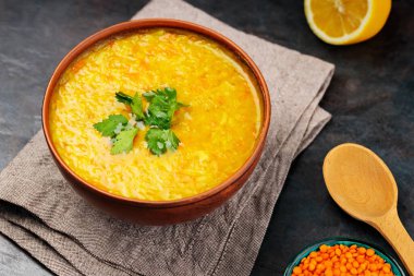 Koyu arkaplanda kırmızı mercimek Hint çorbası. Bir kase mercimek çorbası, malzemeler ve tahta kaşık. Kapat.