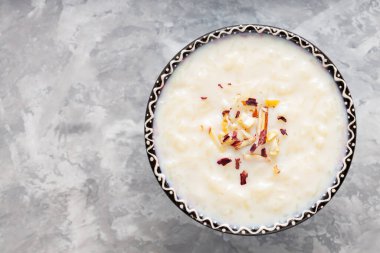 Gri arka planda sütlaçlı kase. Çimentoda kaju fıstığı ve badem ile pirinç kheer. Uzayı kopyala Üst görünüm