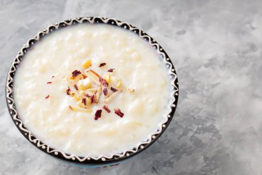 Gri arka planda sütlaçlı kase. Çimentoda kaju fıstığı ve badem ile pirinç kheer. Uzayı kopyala Üst görünüm