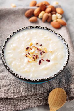 Gri arka planda fındıklı Hint pilavı. İçinde sütlaç ve betonun üzerinde keten peçete olan bir kase. Üst görünüm