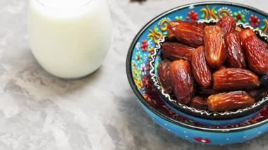 Kurumuş hurma ve gri arka planda süt. Bir kase çimentoda oyulmuş hurma. Ramazan için yemek. Dönen kamera görüntüsü