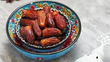 Kurumuş hurma ve gri arka planda süt. Bir kase çimentoda oyulmuş hurma. Ramazan için yemek. Dönen kamera görüntüsü