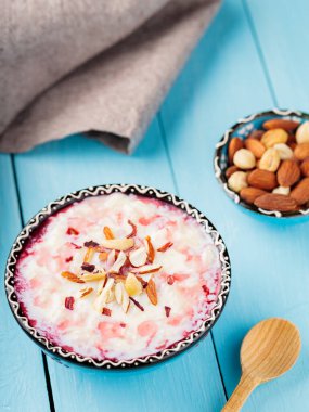 Fındık serpiştirilmiş sütlaç ve gül suyu. Pirinç kheer kase ve ahşap bir masada keten peçete. Geleneksel iftar yemekleri