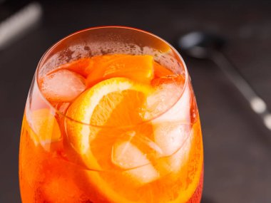 Portakallı ve buzlu Aperol Spritz kokteyli. Siyah arka planda turuncu alkol kokteyli. Kapat.