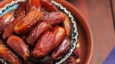 Tahtada çivili hurmalar ve fındıklar. Kasede kurutulmuş hurma, yakın çekim. Ramazan iftar yemeği. Dönen kamera görüntüsü