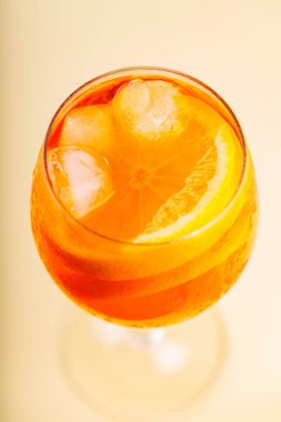 Bej arka planda cam kaplı Aperol Spritz kokteyli. Portakal dilimli ve buzlu Aperol Spritz. Üst görünüm