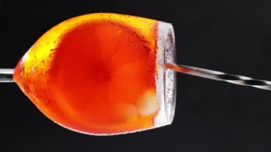 Kokteyl kaşığı bardakta Aperol Spritz karıştırır. Aperol spreyli kokteyl yakın plan. Dikey video