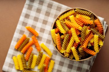 Fusilli kuru makarna ve keten peçete. Çevre kutusunda yeşil, turuncu ve sarı fusilli makarna. İtalyan mutfağı