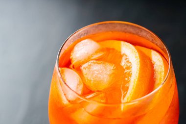 Karanlık arka planda bir bardak Aperol Spritz kokteyli. Portakallı ve buzlu Aperol sprey kokteyli. Boşluğu kopyala