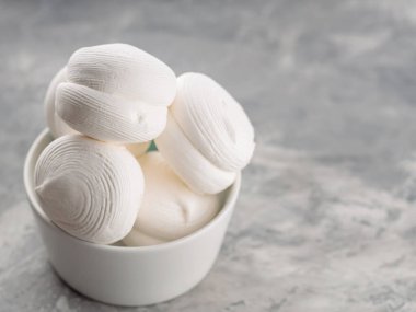 Zephyr lokumları gri arka planda kasede. Betonda tatlı marşmelovları. Boşluğu kopyala