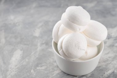 Zephyr lokumları gri arka planda kasede. Betonda tatlı marşmelovları. Boşluğu kopyala