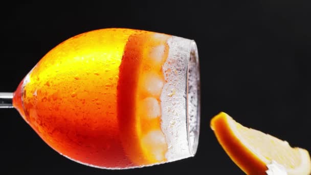 生产Aperol Spritz鸡尾酒的过程 调酒师把带有钳子的橙片和阿培尔 斯普丽兹鸡尾酒放在杯子里 垂直录像 — 图库视频影像
