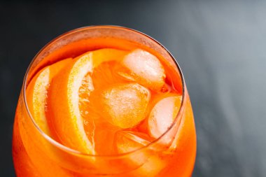 Portakallı ve buzlu Aperol Spritz kokteyli. Siyah arka planda turuncu alkol kokteyli. Kapat.