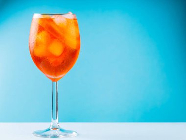 Mavi arka planda cam içinde Aperol Spritz kokteyli. Klasik İtalyan aperatifi, turuncu ve buz küplü Aperol Spritz kokteyli. Boşluğu kopyala