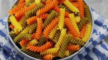 Fusilli kuru makarna kasede, yakın çekim. Betonda ıspanaklı ve domatesli üç renkli fusilli makarna. Bum!