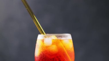 Aperol Spritz kokteyli ve koyu arka planda çevre dostu cam pipet. Portakallı ve buzlu Aperol Spritz kokteyli. Eğil.