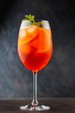 Bardakta Aperol Spritz kokteyli, koyu arkaplanda da turuncu ve taze nane. Geleneksel İtalyan aperatif kokteyli.