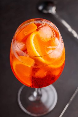 Klasik İtalyan aperatifi Aperol Spritz kokteyli koyu arkaplanda bir dilim portakal. Geleneksel İtalyan aperatif kokteyli konsepti. Kapat.