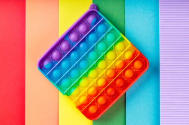 Renkli popo gökkuşağı arka planında oyuncağı kıpırdatıyor. LGBT eşit haklar hareketi ve cinsiyet eşitliği kavramı. Üst görünüm