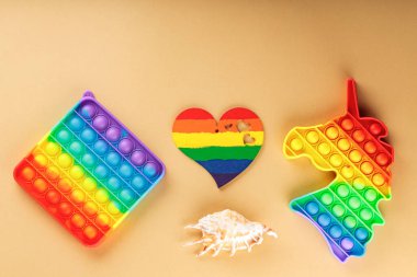 Çok renkli oyuncaklar ve bej arka planda gökkuşağı kalbi. LGBT eşit haklar hareketi ve cinsiyet eşitliği kavramı. Üst Manzara. Boşluğu kopyala