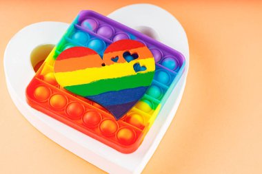 Gökkuşağı kalbi, beyaz kalp ve mercan arka planda oyuncak. LGBT eşit haklar hareketi ve cinsiyet eşitliği kavramı. Boşluğu kopyala