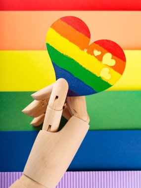 Yapay kol, çok renkli lgbt bayrağında gökkuşağı kalbini tutuyor. LGBT Gurur ayı konsepti