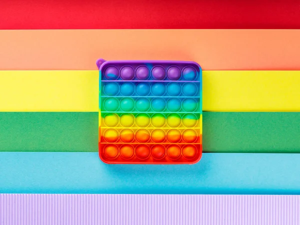 Renkli popo gökkuşağı arka planında oyuncağı kıpırdatıyor. LGBT eşit haklar hareketi ve cinsiyet eşitliği kavramı. Üst görünüm