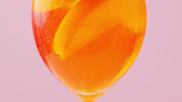 Pembe Arka Planda Bir Bardak Aperol Spritz Kokteyli Portakallı Buzlu — Stok video