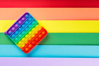 Renkli popo gökkuşağı arka planında oyuncağı kıpırdatıyor. LGBT eşit haklar hareketi ve cinsiyet eşitliği kavramı. Boşluğu kopyala