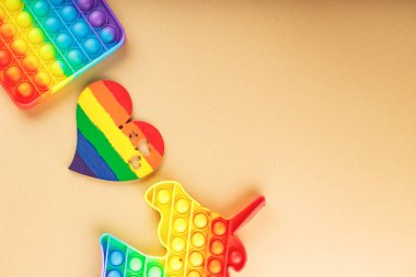 Çok renkli oyuncaklar ve bej arka planda gökkuşağı kalbi. LGBT eşit haklar hareketi ve cinsiyet eşitliği kavramı. Üst Manzara. Boşluğu kopyala
