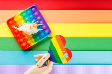Gökkuşağı arka planında LGBT bayrağı renginde kalp. Yapay kol gökkuşağı kalbini tutar. LGBT kurtuluş kavramı