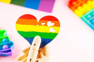 Pembe arka planda LGBT bayrağı renginde kalp. Yapay kol gökkuşağı kalbini tutar. LGBT Gurur ayı konsepti