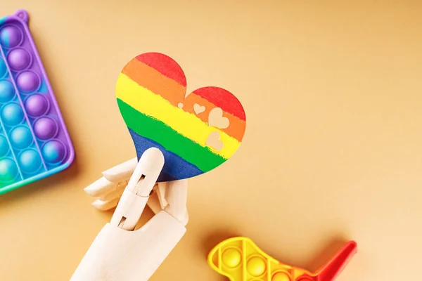 stock image Heart in colors of LGBT flag on beige background. Rainbow heart in artificial arm. LGBT Pride month concept. Copy space