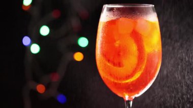 Bardağın üzerine Aperol Spritz ile su sıçramış. Bir bardak Aperol Spritz kokteyli. Renkli bir arka planda. Statik çekim