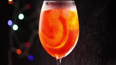 Bardağın üzerine Aperol Spritz ile su sıçramış. Bir bardak Aperol Spritz kokteyli. Renkli bir arka planda. Statik çekim