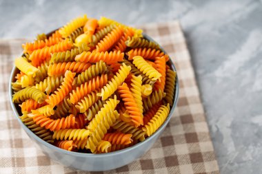 Beton üzerine çiğ fusilli makarna. Keten peçeteye üç renk rotini veya fusilli makarna. İtalyan yemeği.