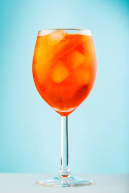 Mavi arka planda cam içinde Aperol Spritz kokteyli. Klasik İtalyan aperatifi, turuncu ve buz küplü Aperol Spritz kokteyli. Kapat.