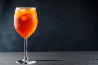 Bardakta Aperol Spritz kokteyli ve koyu ahşap tahtalarda taze turuncu. Şarap kadehinde servis edilen bir bardak Aperol Spritz kokteyli. Boşluğu kopyala
